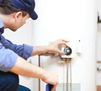 A tech responding to a common water heater problem in Colorado Springs by adjusting thermostat.