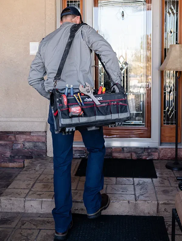 Technician with tools walking up to residential home in Colorado Springs, CO.