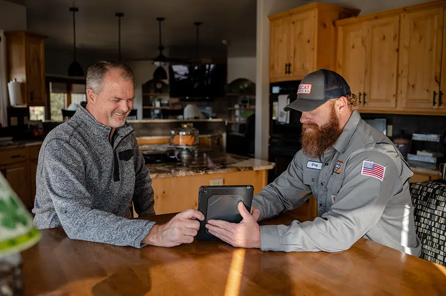 Technician helping customer at dining room table in Colorado Springs, CO.