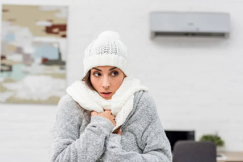 woman wearing coat, scarf and hat inside because no heat at home in Colorado Springs