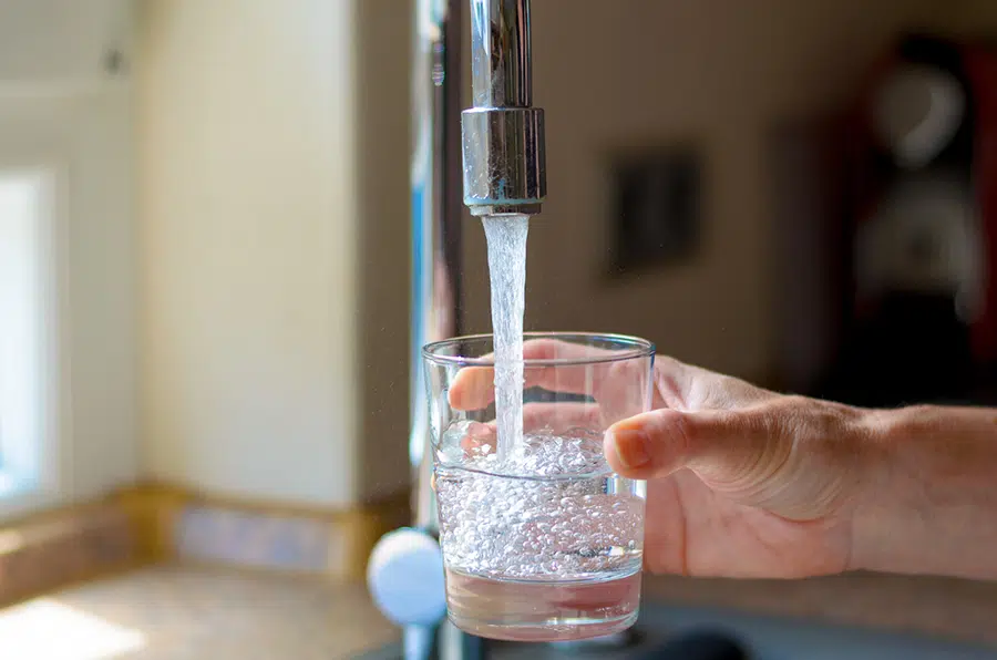 person filling water glass with clean drinking water
