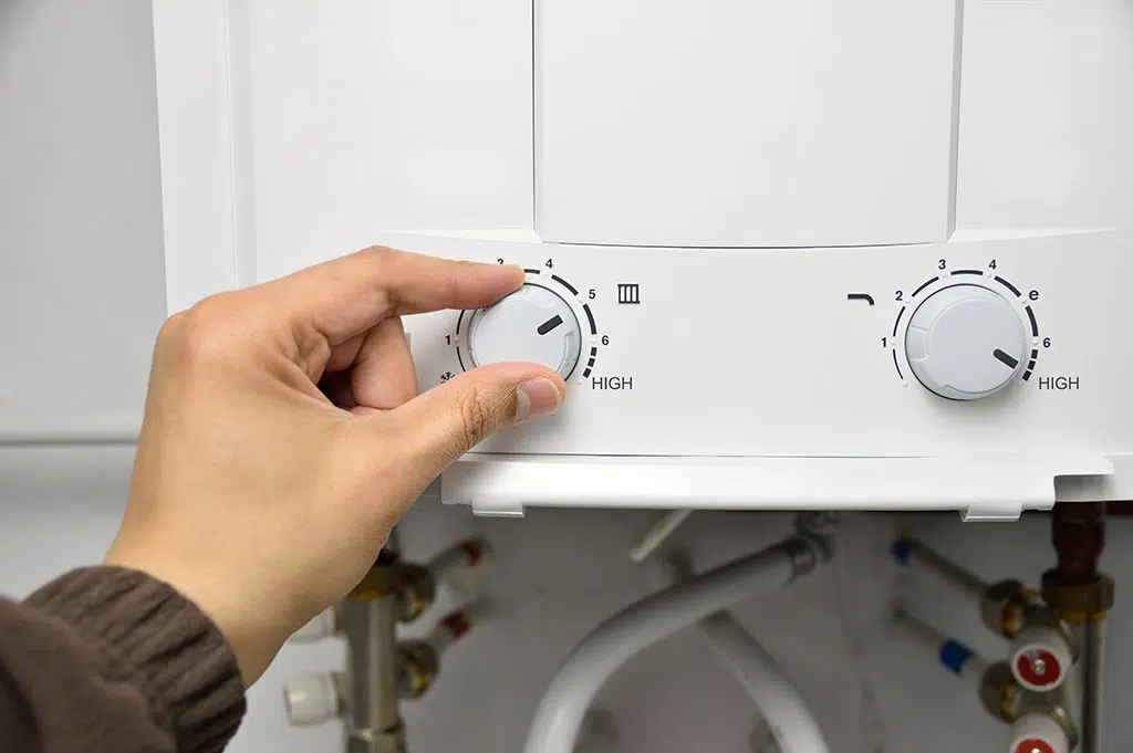 person adjusting thermostat on water heater